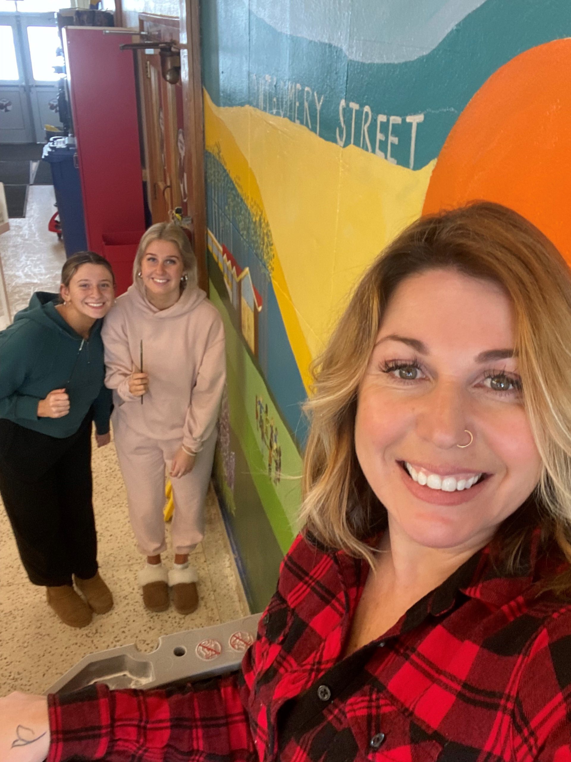 Artist Connie Wheaton and two of her student helpers at the new mural she painted in the Montgomery Street Elementary School front entrance.