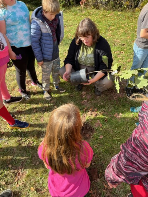 A teacher and students plant a tree at Cambridge-Narrows Community School during Take Me Outside Day, Oct. 18, 2023.