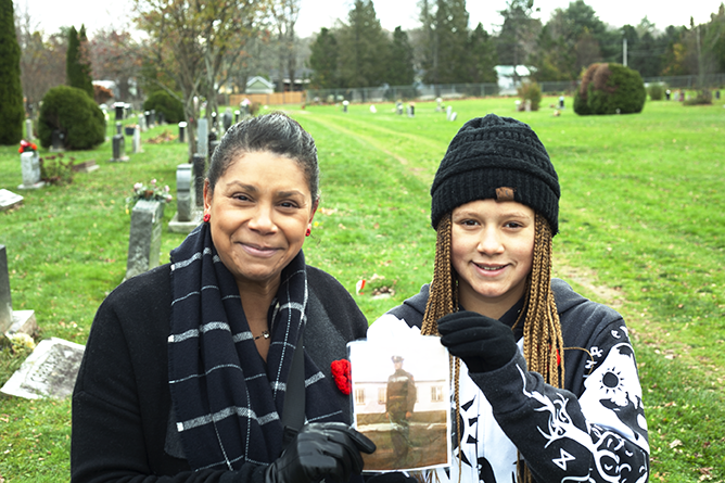 Andrea Izzard and her daughter Marcela Izzard-Imocanin hold a photo of Andrea's father (and Marcela's grandfather) Joseph Richard Izzard, at the No Stone Left Alone ceremony at the St. Vincent De Paul Cemetery in Oromocto, Nov. 9, 2023.