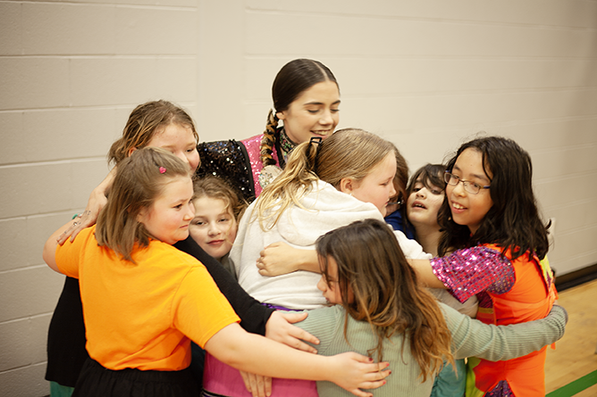 Abby Brooks, a teacher and fancy shawl dancer from Sitansisk/St. Mary’s First Nation, in a group hug with her dancers after an Indigenous dance at Gibson-Neill Memorial Elementary School on Friday, Feb. 2, 2024.