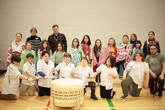 ASD-W Director of Curriculum and Instruction Dianne Kay (back row, second) and ASD-W Superintendent David McTimoney (back row, third) stand with students and their instructors after an Indigenous dance recital at Gibson-Neill Memorial Elementary School on Friday, Feb. 2, 2024.