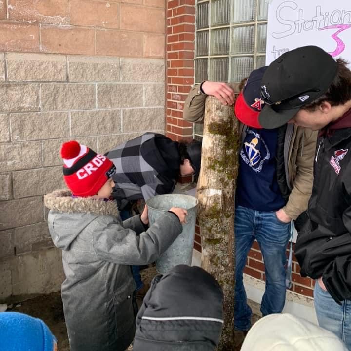 Grade 12 Leadership students at Stanley Consolidated School teach younger students how to tap trees and collect sap to make maple syrup, on March 27, 2024.