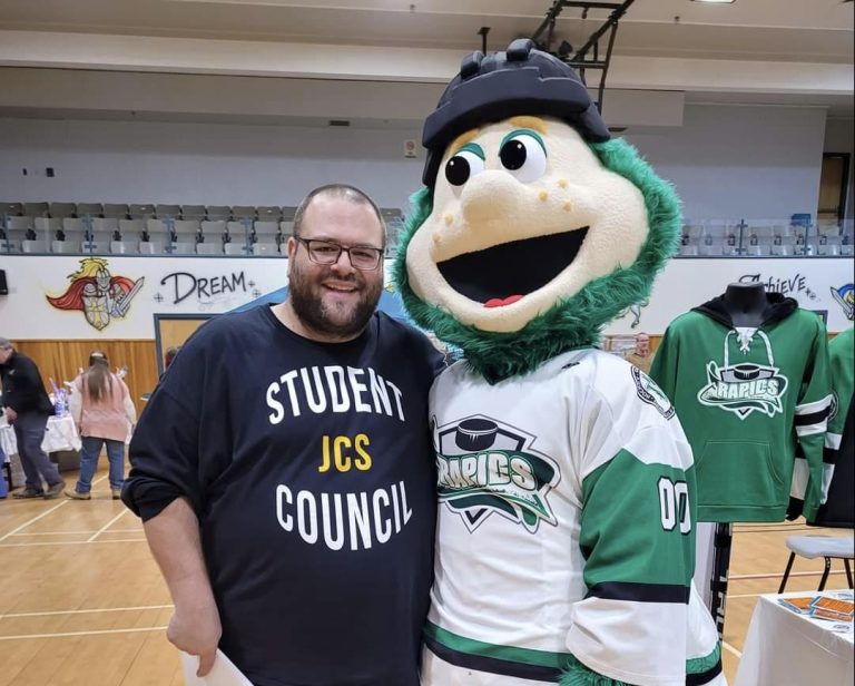 John Caldwell School teacher Marco Leblanc stands with Rapido, the mascot of the Grand Falls Rapids hockey team. Leblanc is one of six recipients of Grand Falls' new volunteer recognition award, Community Grandioses.