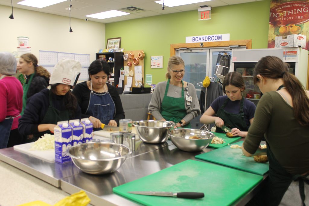 Shauna Miller, a registered public health dietitian with Horizon Health Network, works with Devon Middle School Grade 7 students during their visit to Fredericton's Greener Village community kitchen. Miller is a member of Horizon’s Health Promotion Population Health (HPPH) Team, which created the food insecurity curriculum for use in schools, as well as the poster contest.