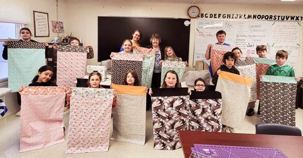 Keswick Ridge School students display the "hot dog" pillowcases they learned to sew during the school's three-week-long Enrichment Wednesday Afternoons in March and April.