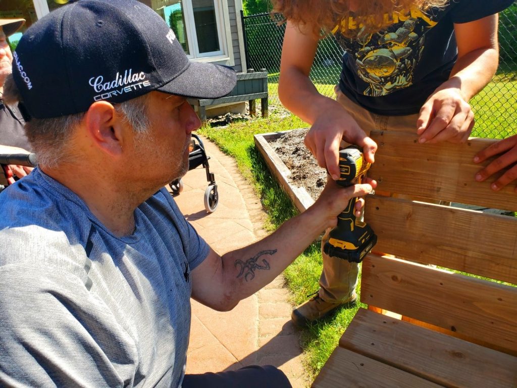 Students from Stanley Consolidated School work with seniors at Nashwaak Villa on May 30 to build benches at the location.