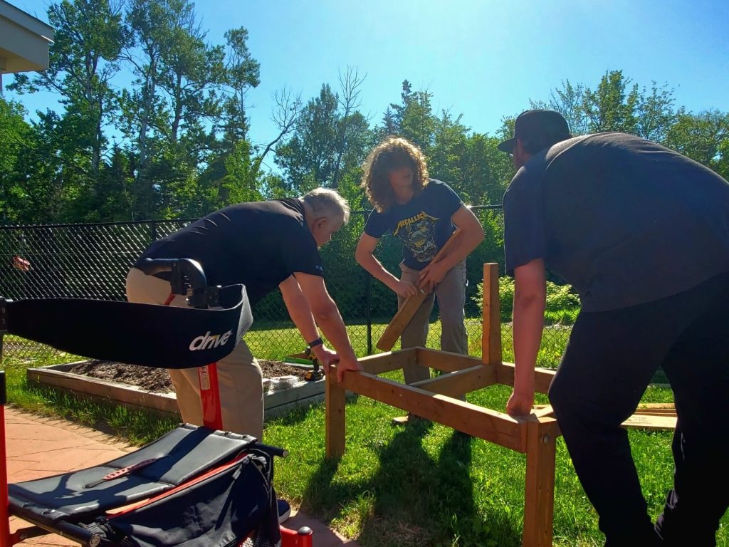 Students from Stanley Consolidated School work with seniors at Nashwaak Villa on May 30 to build benches at the location. The initiative was part of a Develop and Lead Doership project initiated by Stanley Consolidated School Skilled Trades teacher Michael Valk.