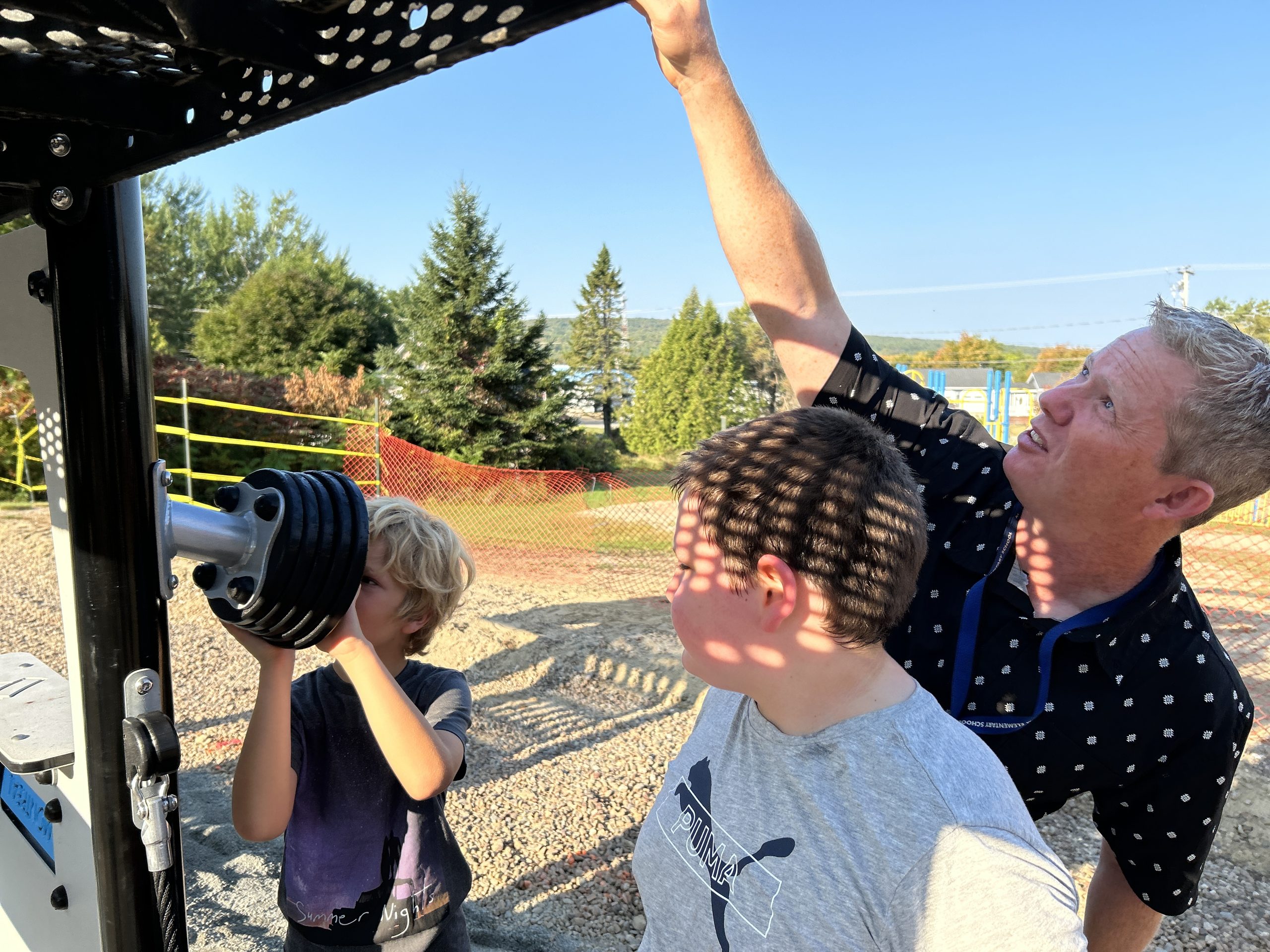 McAdam Elementary School Principal Scott Cousins and several students inspect the new equipment being installed on the school's playground.