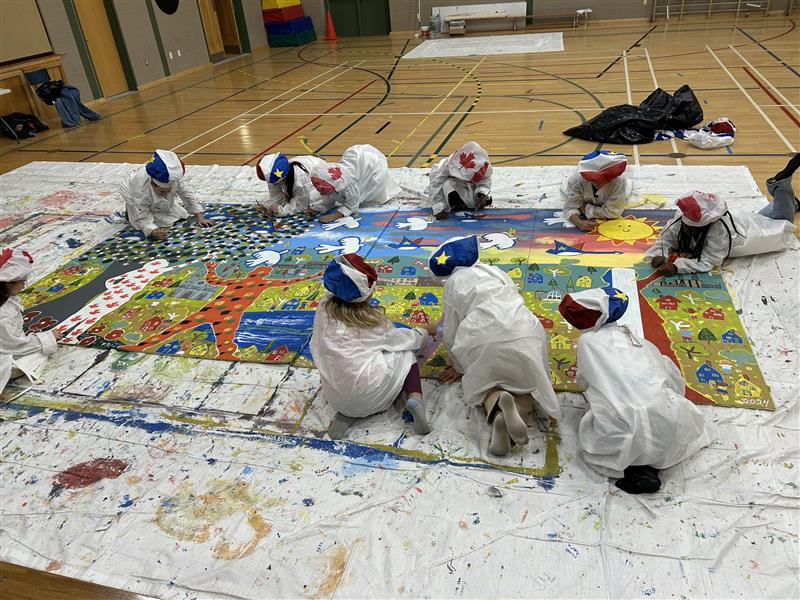 Students of both Saint Mary's Academy and Carrefour de la Jeunesse create a joint mural as part of the Create to Get Closer mural painting project at Carrefour de la Jeunesse in Edmundston on Oct. 8, 2024. The mural will eventually be displayed in Edmundston as a symbol of community across the two official languages and different cultures. Photo Credit: Bethany Toner