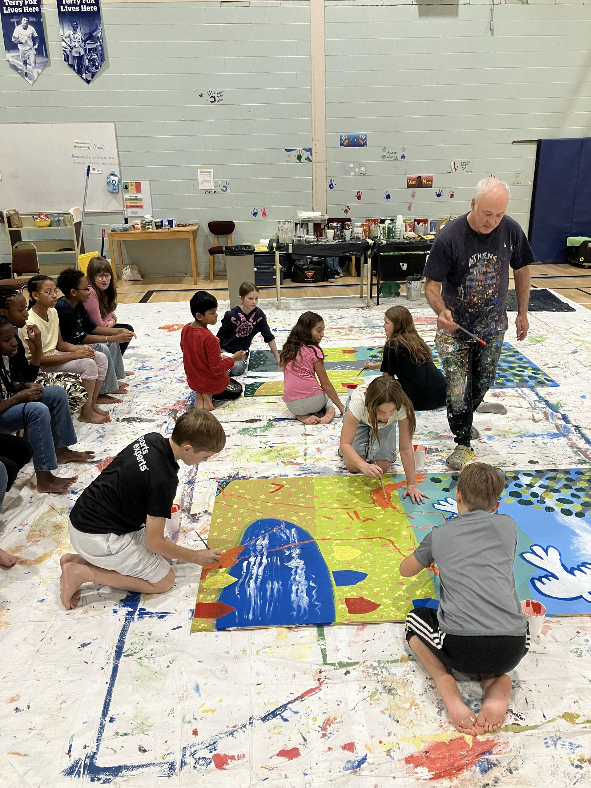 Saint Mary's Academy (SMA) students work with artist Jean-Pierre Arcand to create a mural as part of the Create to Get Closer mural painting project at the school in Edmundston on Oct. 7, 2024. Photo Credit: Emily McLaughlin-Toner