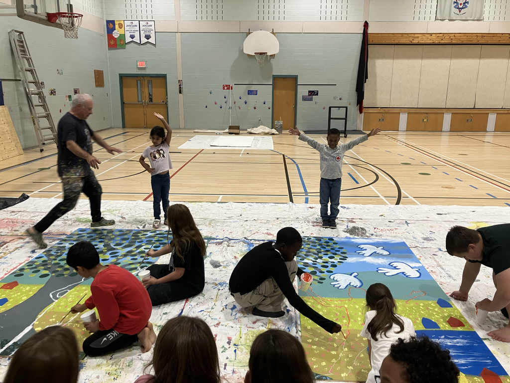 Saint Mary's Academy (SMA)  students create a mural as part of the Create to Get Closer mural painting project at the school in Edmundston on Oct. 7, 2024. On Oct. 8, eight SMA student ambassadors visited their counterparts at francophone Carrefour de la Jeunesse to collaborate on the mural they created. The combined anglophone-francophone student mural will eventually be displayed in Edmundston as a symbol of community across the two official languages, and across different cultures. Photo Credit: Emily McLaughlin-Toner 