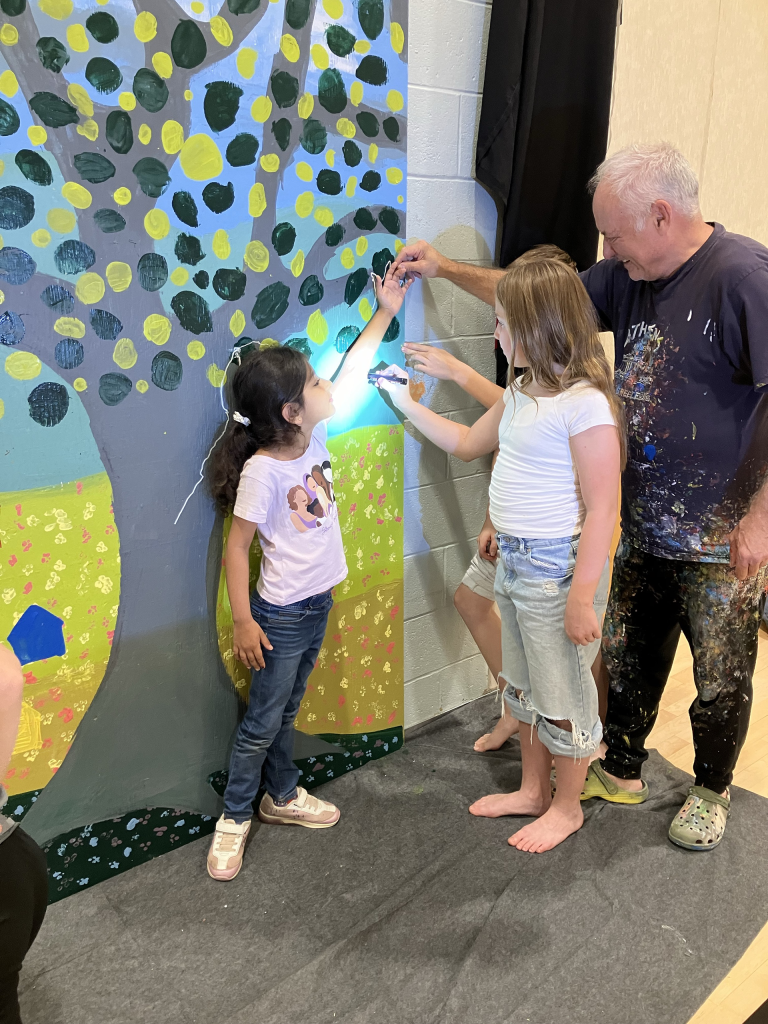 Saint Mary's Academy (SMA) students work with artist Jean-Pierre Arcand to create a mural as part of the Create to Get Closer mural painting project at the school in Edmundston on Oct. 7, 2024. Photo Credit: Emily McLaughlin-Toner