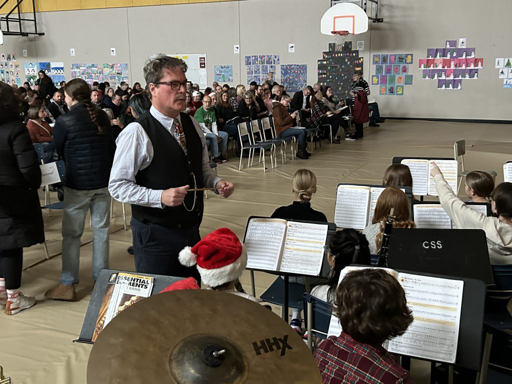 Teacher Andrew Rogers prepares to lead the Connaught Street School concert band during the school's holiday concert on Wednesday, Dec. 11, 2024. Before the ceremony, Rogers' sister, Fredericton Mayor Kate Rogers, presented him with the King Charles III Coronation Medal for having made a significant contribution to his community, province, and country as a master bagpiper and educator. 