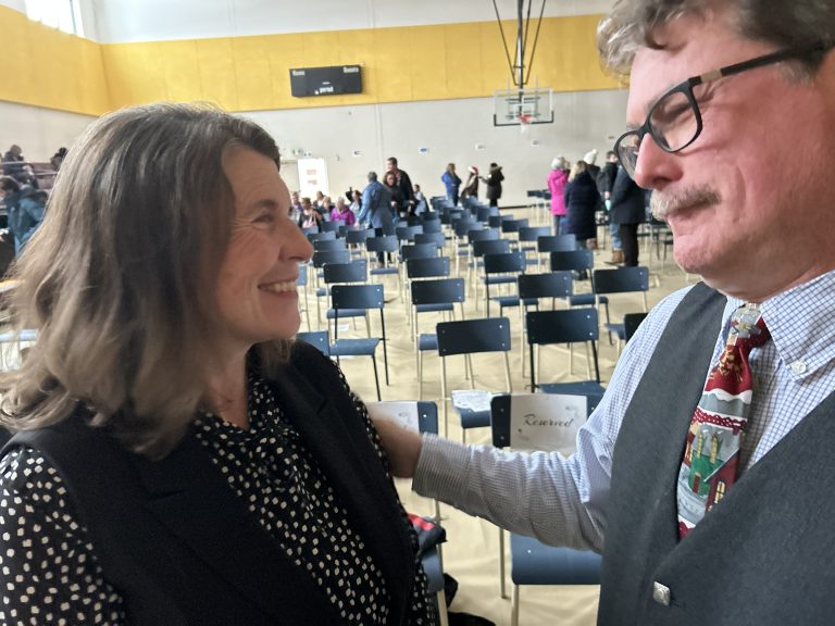 (L-R) Fredericton Mayor Kate Rogers congratulates her brother, teacher Andrew Rogers, on his receiving the King Charles III Coronation Medal for having made a significant contribution to his community, province, and country as a master bagpiper and educator. The presentation occurred on Wednesday, Dec. 11, before the Connaught Street School holiday concert.