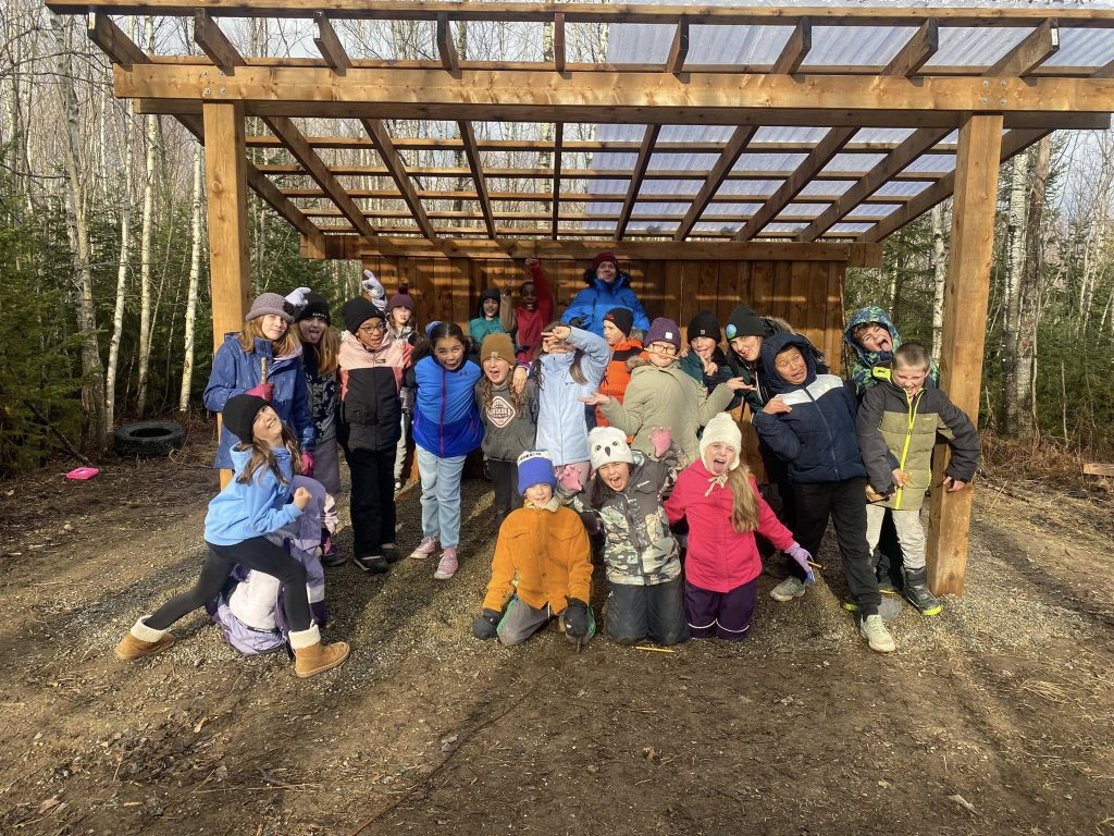 Teacher Vanessa Després's Grade 4/5 students pull faces under the gazebo of Saint Mary's Academy's new outdoor classroom. The outdoor classroom, built in the fall by district staff and students, also includes 14 benches made from dead standing trees and a teacher stand. Photo Credit: Vanessa Després.