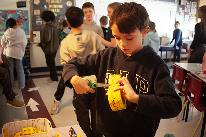 A students cuts tickets at the games arcade Teacher Kristen Nixon's Grade 5 class created at Connaught Street School.