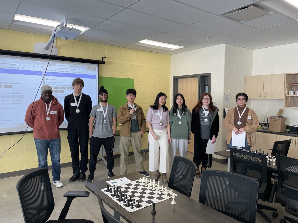 2025 FEC/OEC high school chess tournament winners (L-R): Fanuel Komi (Grade 12 Silver), Chris Kozlowski (Grade 9 Gold), Rajveer Singh Rekhi (Grade 11 Silver), Enming Zhang (Grade 11 Gold), Iris Chen (Grade 12 Gold), Fifi Chen (Grade 10 Gold), Roland Brooks (Grade 9 Silver), and Pietra De Lucca (Grade 10 Silver). 