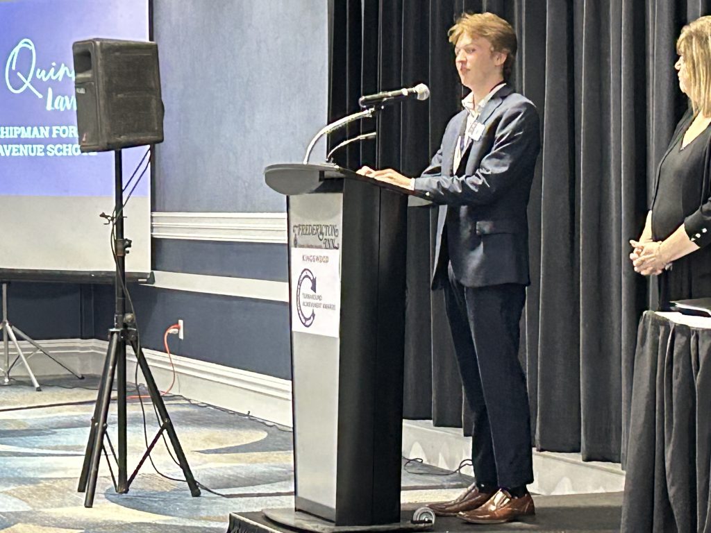 Chipman Forest Avenue School (CFAS) Grade 12 student Quinn Lavigne addresses the audience at last night's Turnaround Achievement Awards ceremony at the Fredericton Inn, as CFAS Principal Yvonne Caverhill looks on.
