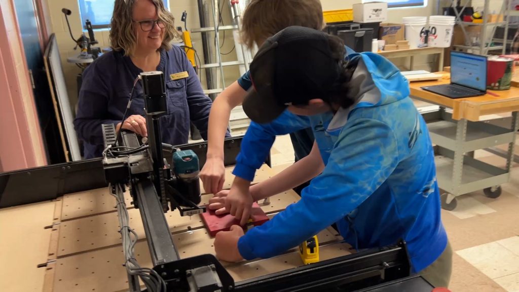 ASD-W Digital Learning Lead Wendy Thomas works with students to carve out a physical QR Code using an X-Carve machine.