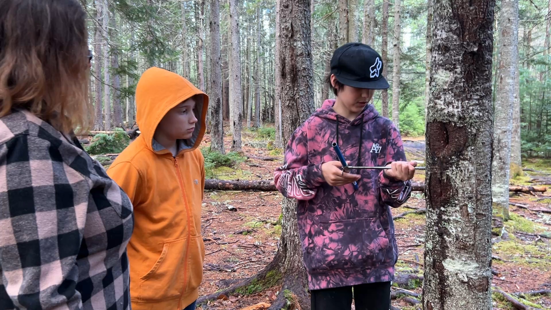 ASD-W Experiential Learning Lead Natalie Mombourquette guides students as they take a tree core sample on the forest pathway behind the Cambridge-Narrows Community School.