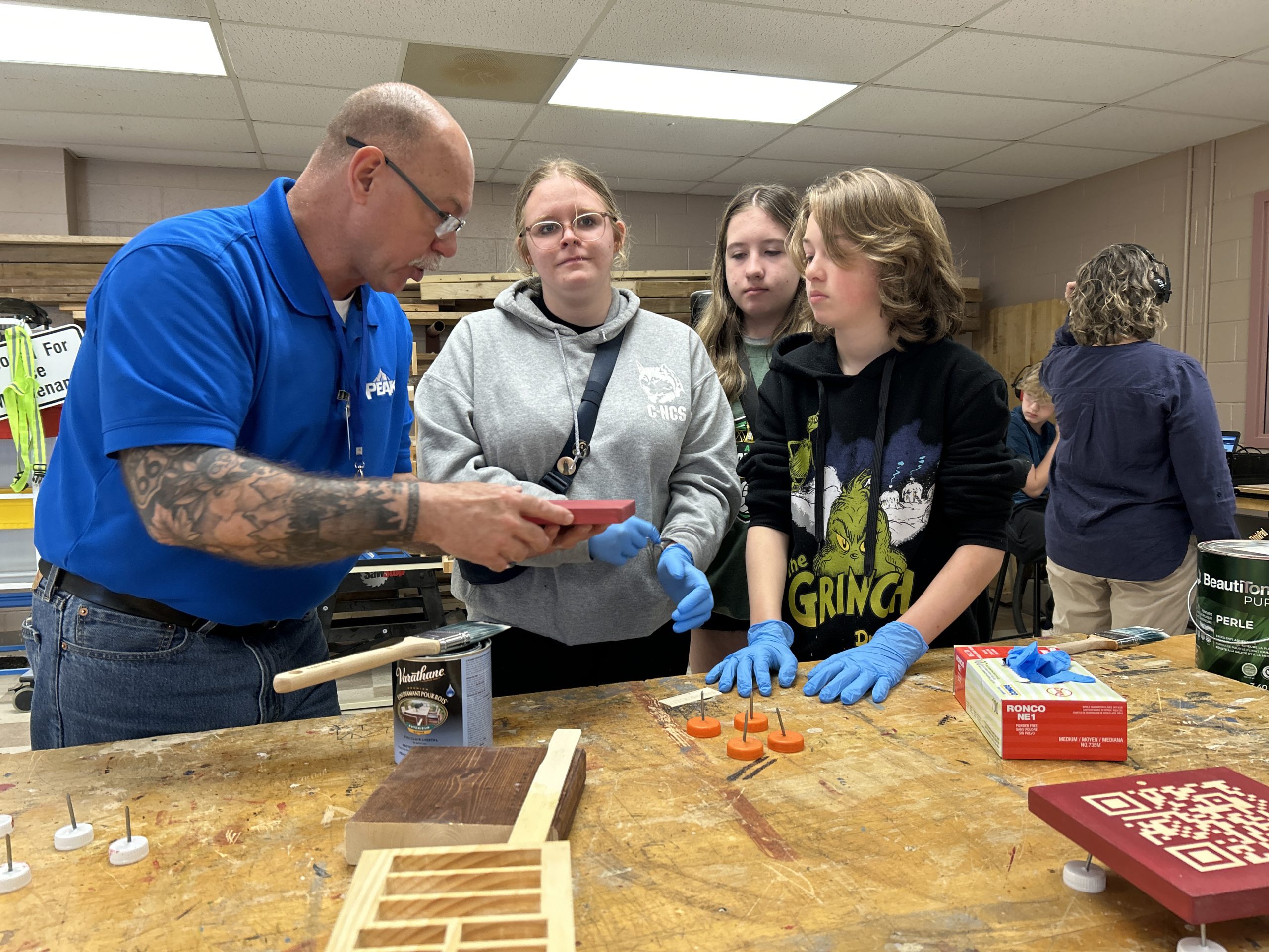 ASD-W Digital Learning Lead Luc Plourde works with students to finish their wooden QR Codes.