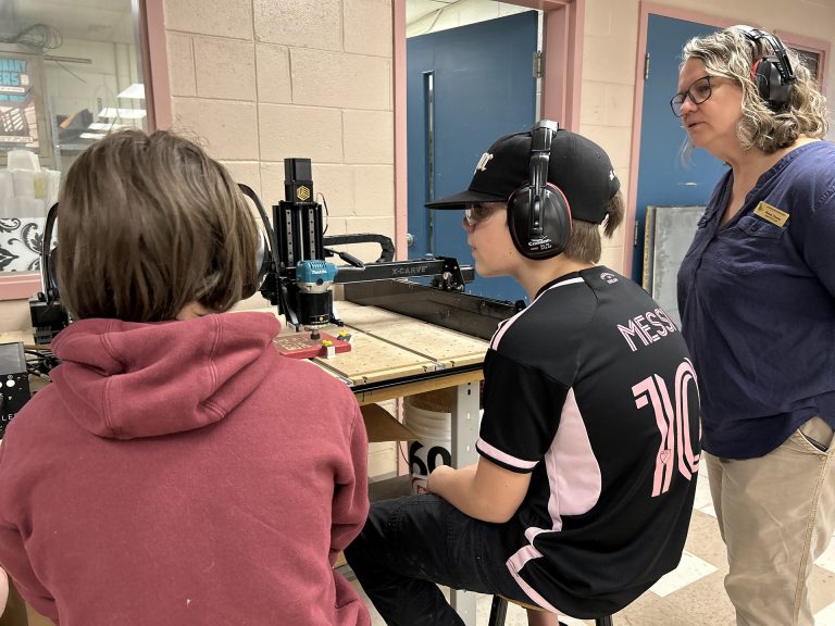 ASD-W Digital Learning Lead Wendy Thomas works with students at Cambridge-Narrows Community School to carve out a physical QR Code using an X-Carve machine.